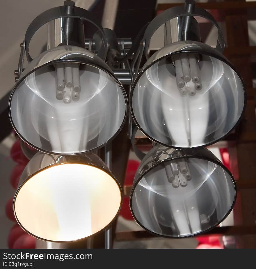 Four metal lamps on a ceiling in trade centre, closeup