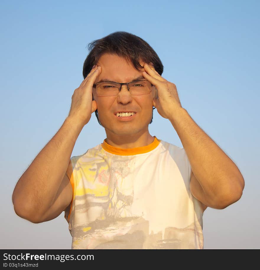 Young man with a headache against blue sky