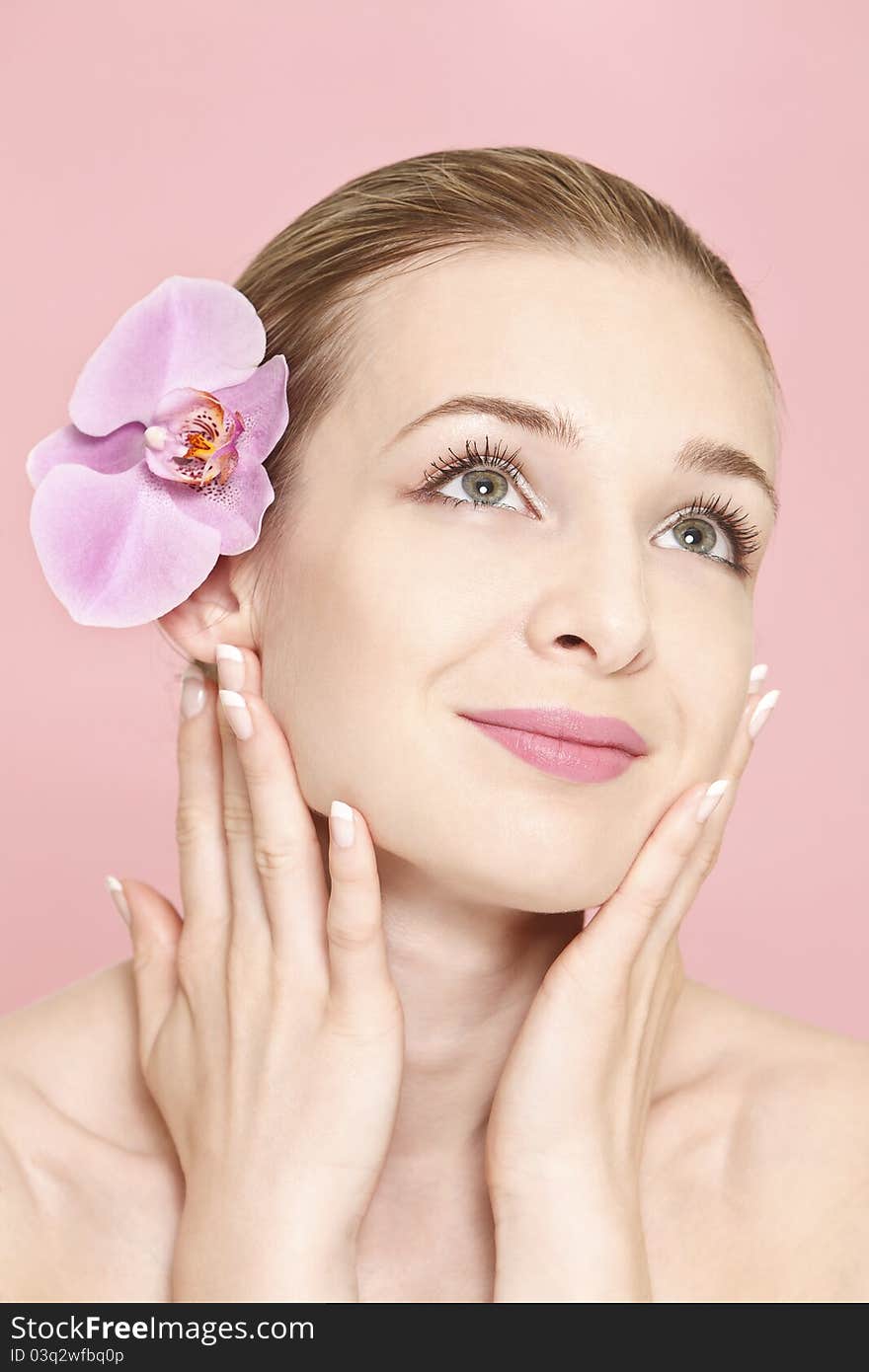 Portrait of a fresh and lovely woman with a pink orchid