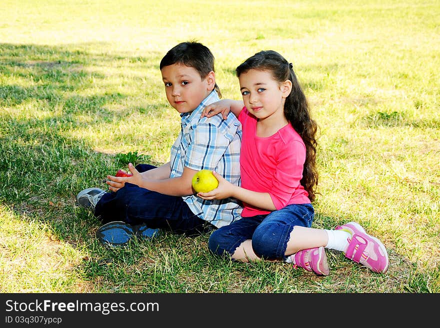 The boy with the girl play sitting on a grass in park