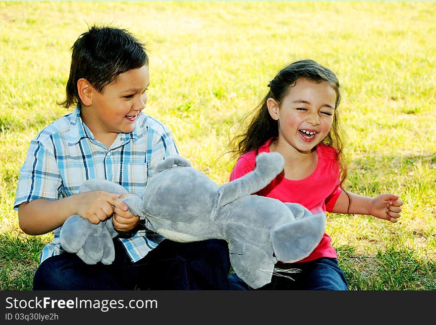 The boy with the girl play sitting on a grass in park