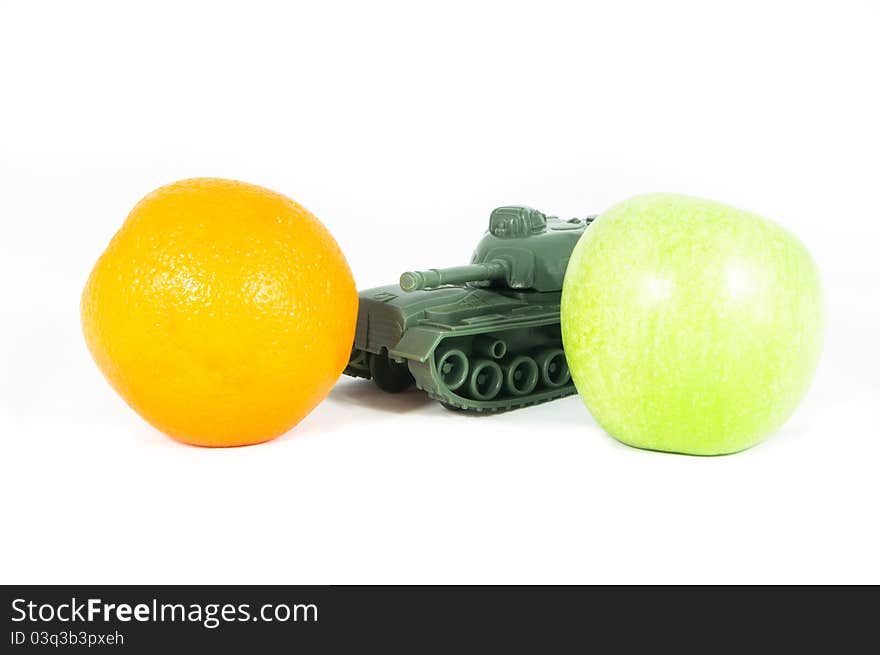 Front view of a toy tank protecting a green apple and an orange. Front view of a toy tank protecting a green apple and an orange