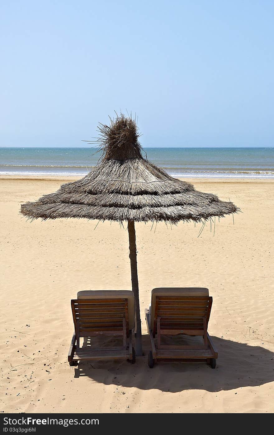 Umbrella and two chairs on the sand beach