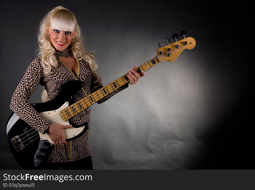 Blonde girl with electric guitar in his hands on a black background