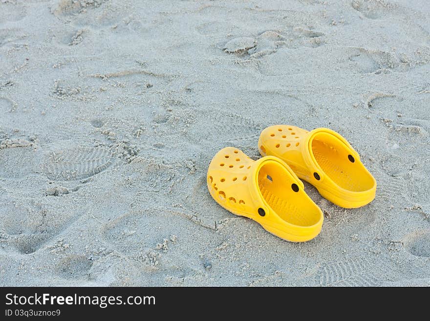 Bright yellow flip-flops on sand beach