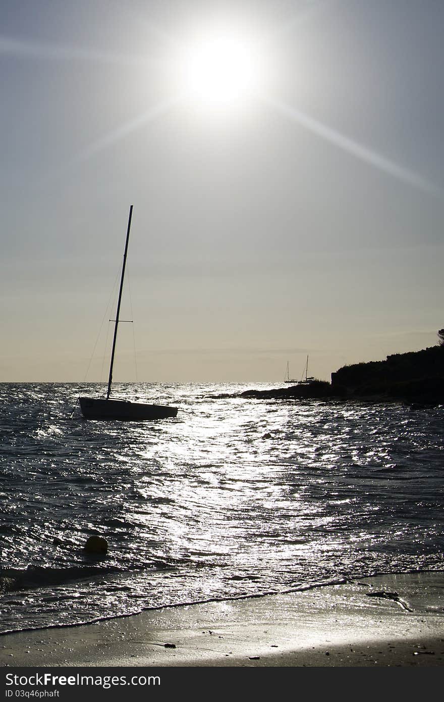 Sailing boat after sunrise in back-light, shooting from the beach. Sailing boat after sunrise in back-light, shooting from the beach