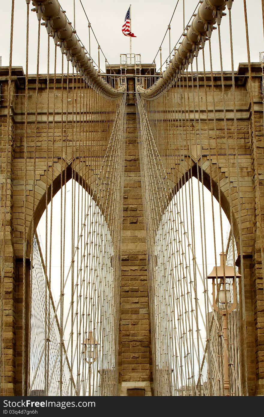 Brown toned detail photo of Brooklyn Bridge in New York City, waving American flag. Brown toned detail photo of Brooklyn Bridge in New York City, waving American flag