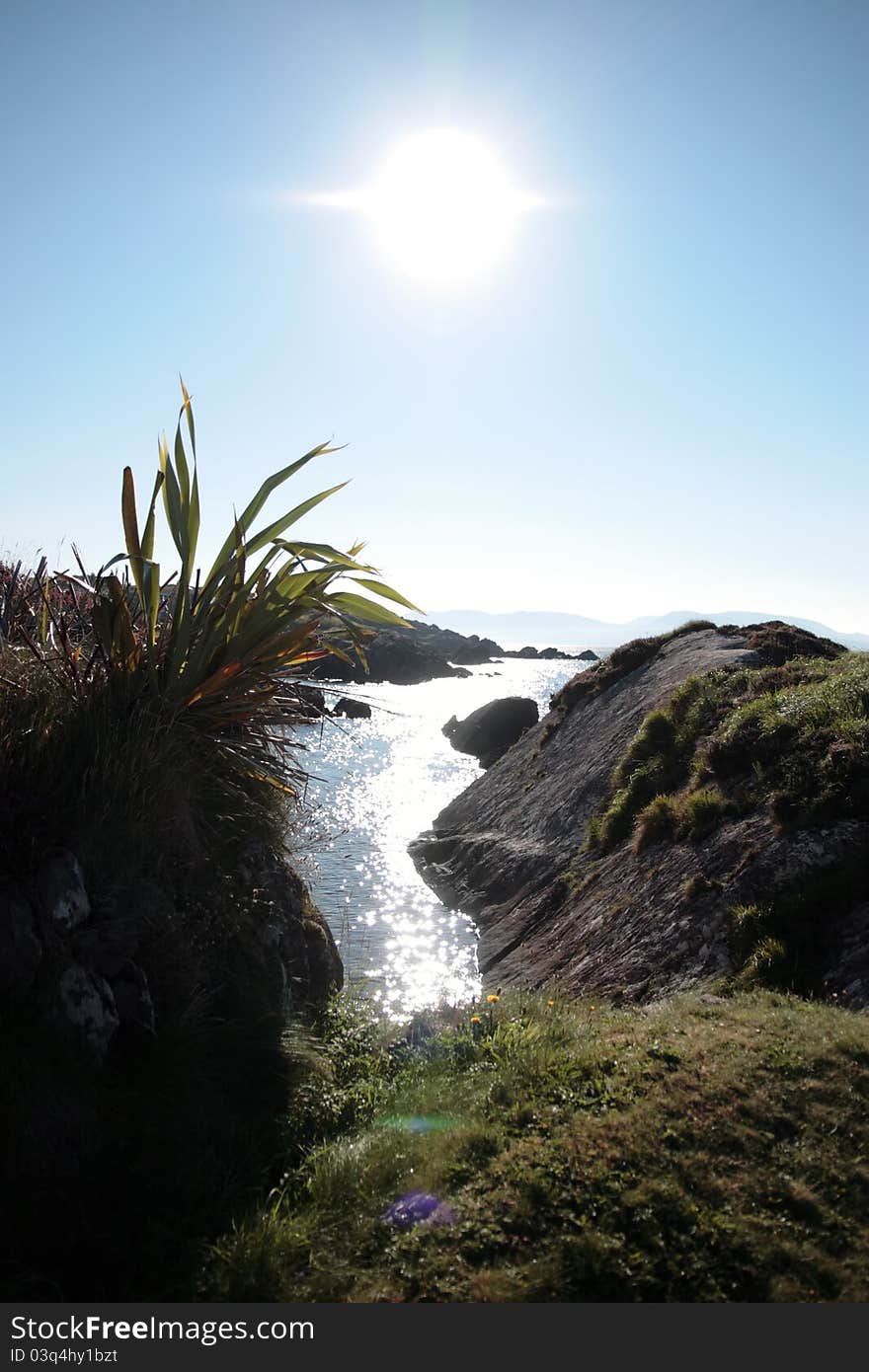 Scenic view in kerry ireland of rocks and sea with mountains against a beautiful bright sunny sky. Scenic view in kerry ireland of rocks and sea with mountains against a beautiful bright sunny sky