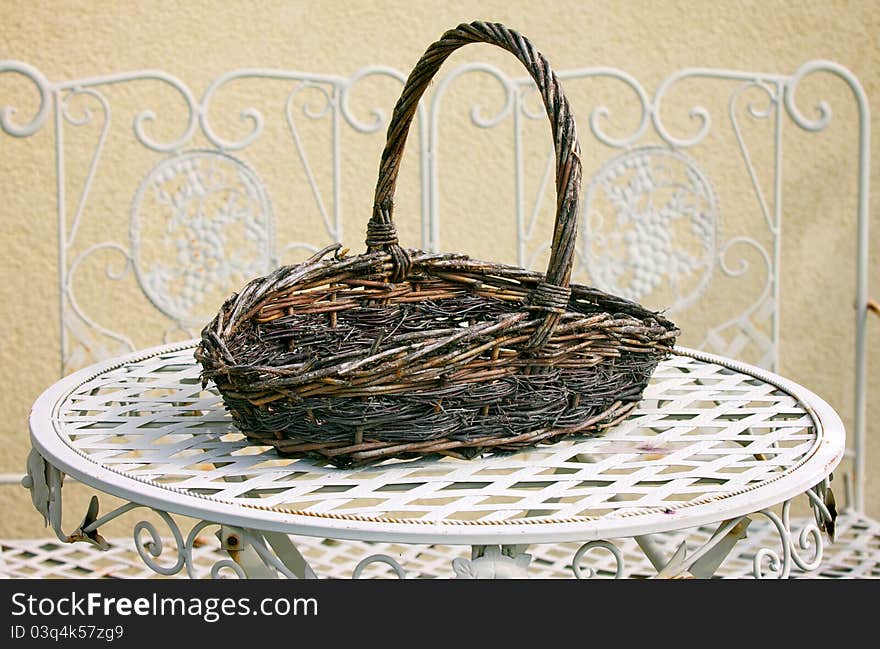 Decorative wicker basket on white metal table in home garden