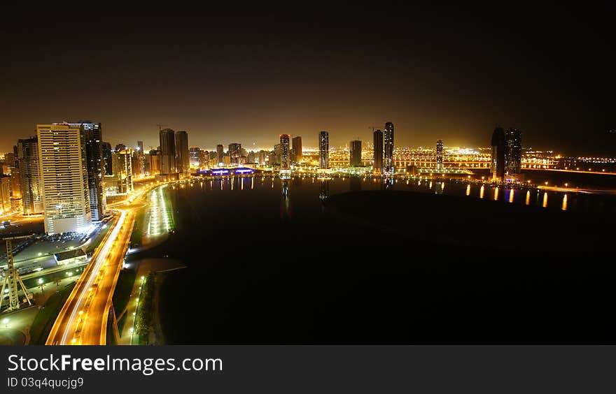 Night view of Al-Khan lake in Sharjah. Surrounding view high rise buildings reflected on the waters. Dubai is visible in the backround. Night view of Al-Khan lake in Sharjah. Surrounding view high rise buildings reflected on the waters. Dubai is visible in the backround