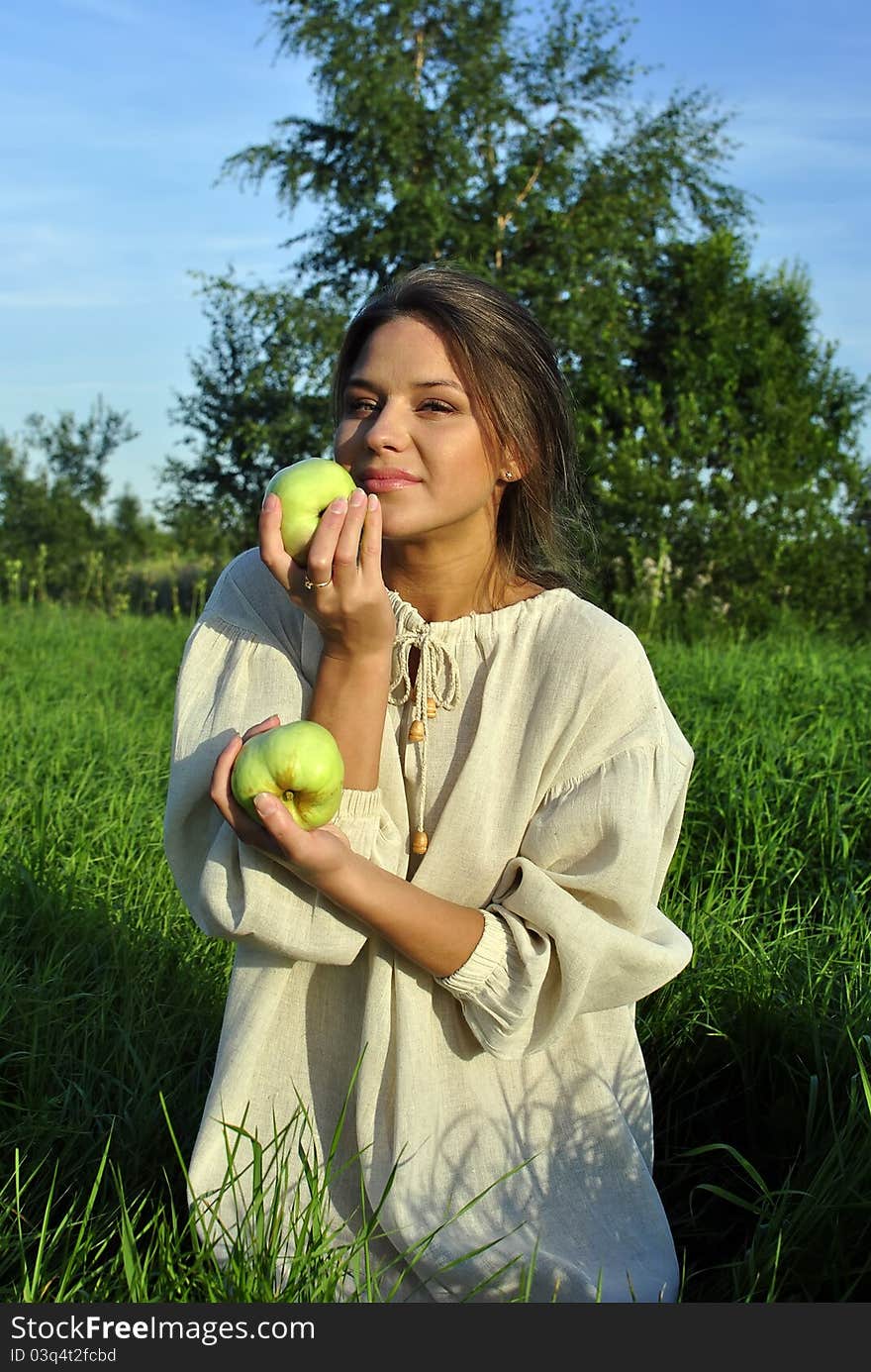 Girl in a linen shirt, holding apples