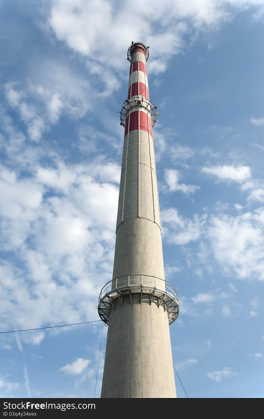 Clean factory chimney on blue sky with white clouds