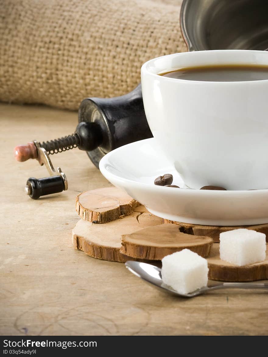 Cup of coffee and grinder with roasted beans