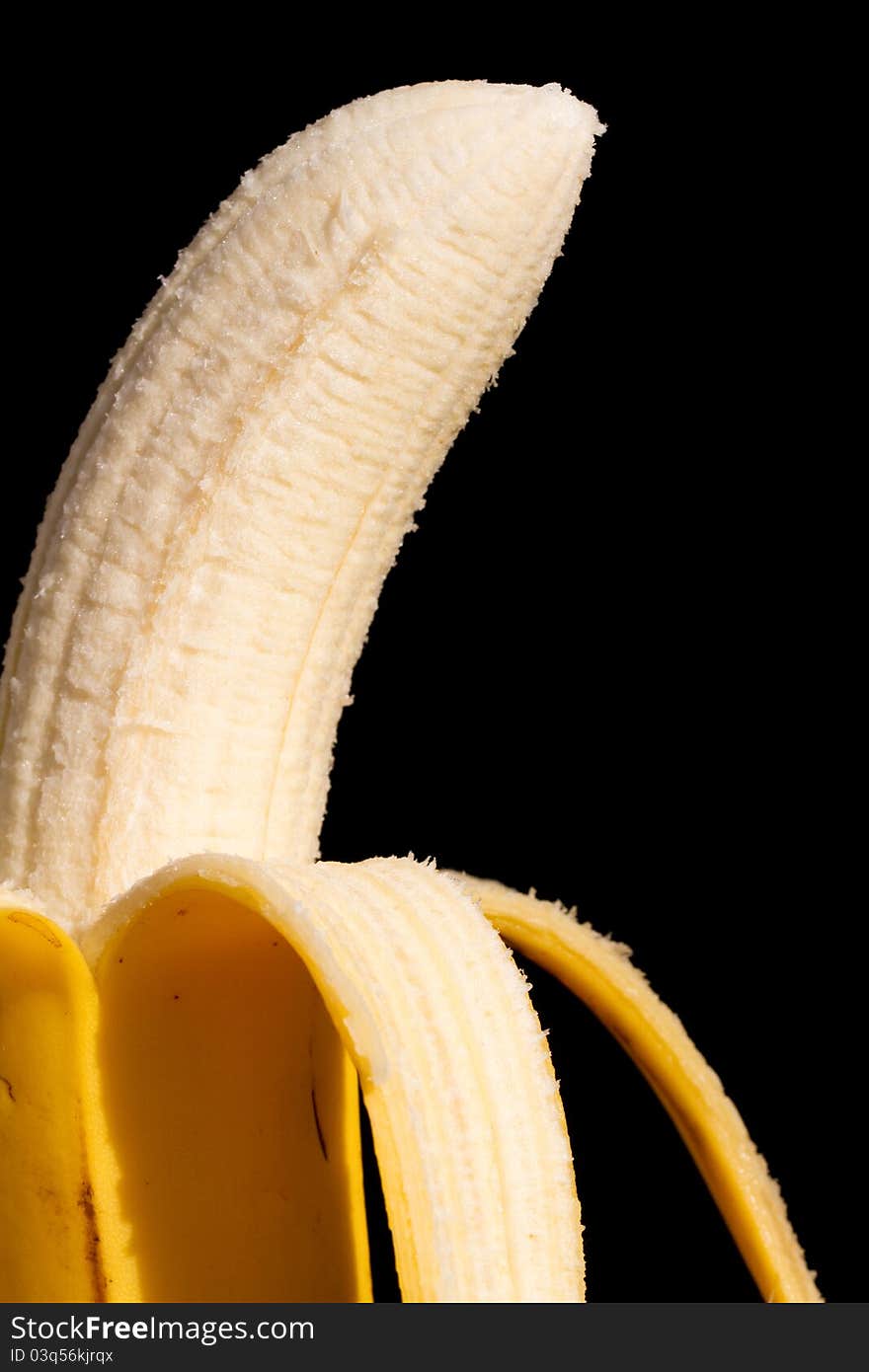 A half pealed banana close up with a black background