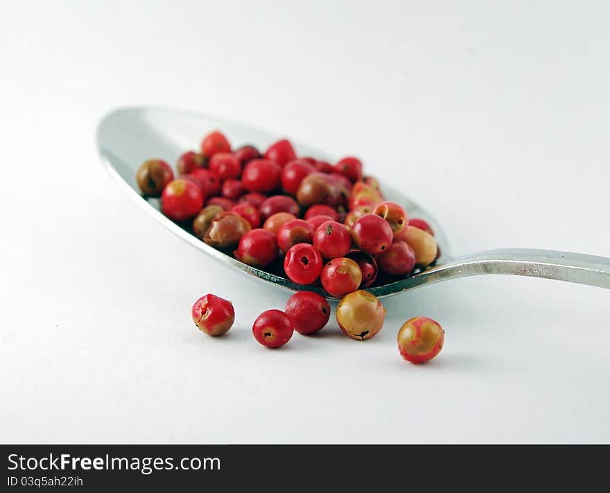 Whole red peppercorns on a spoon