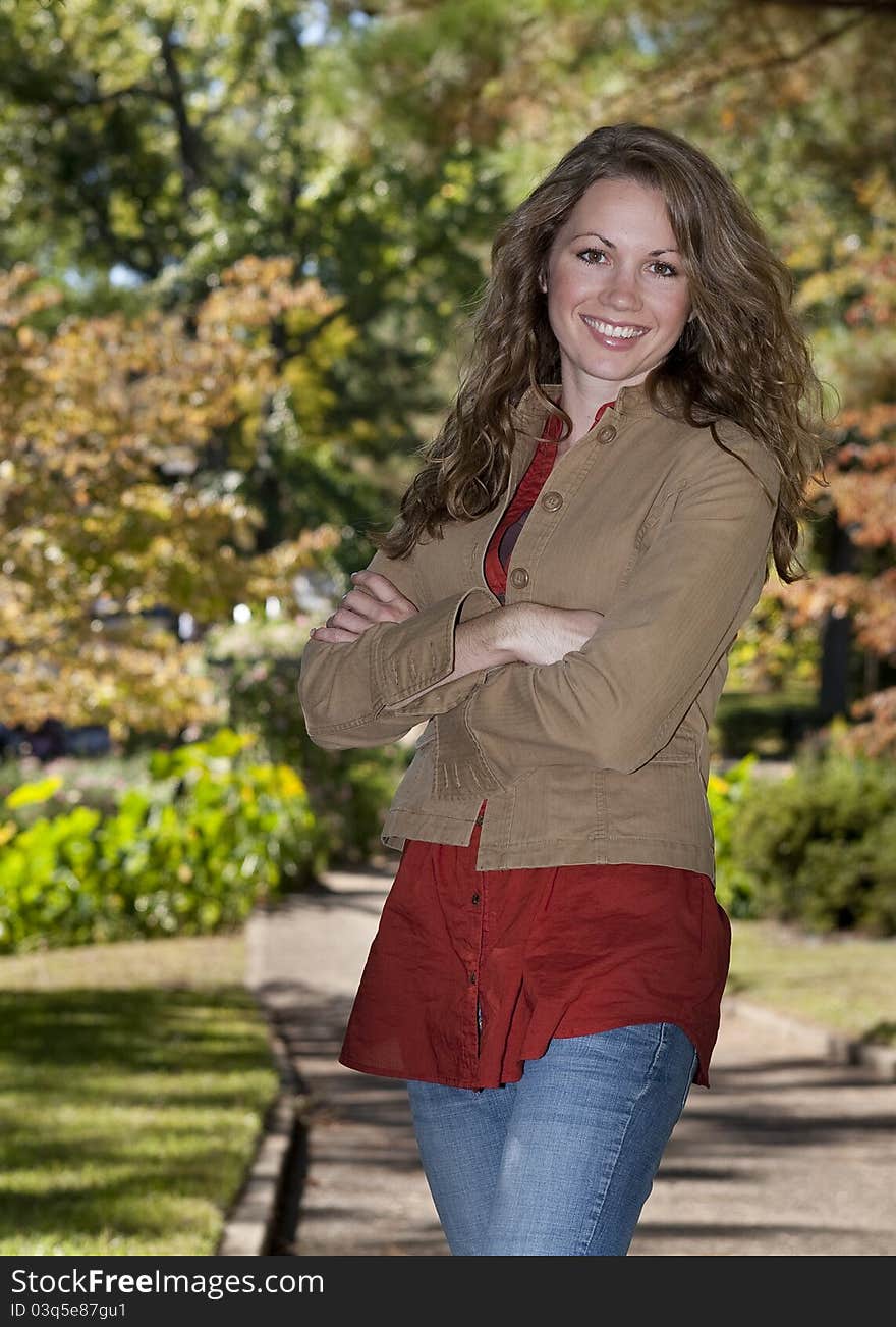 Young woman standing with arms folded in park at autumn. Young woman standing with arms folded in park at autumn