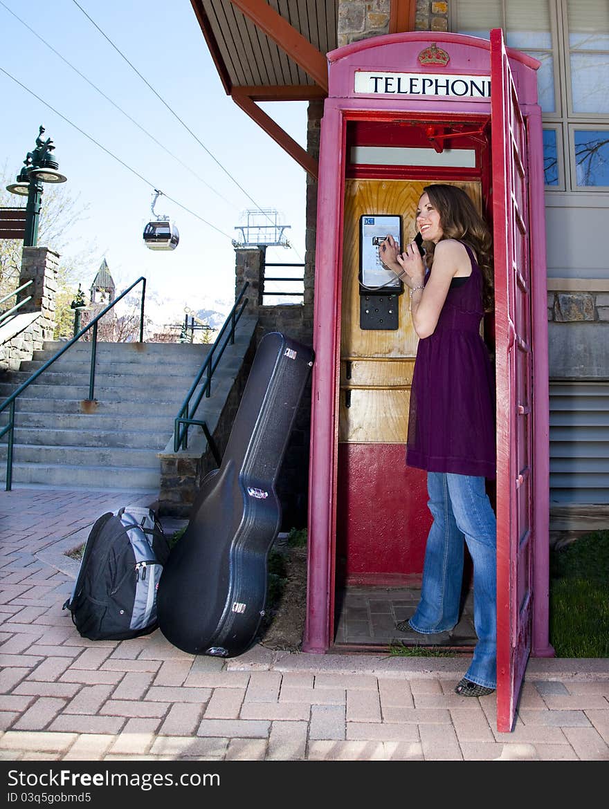 Young woman calling from a phone booth at a ski resort. Young woman calling from a phone booth at a ski resort