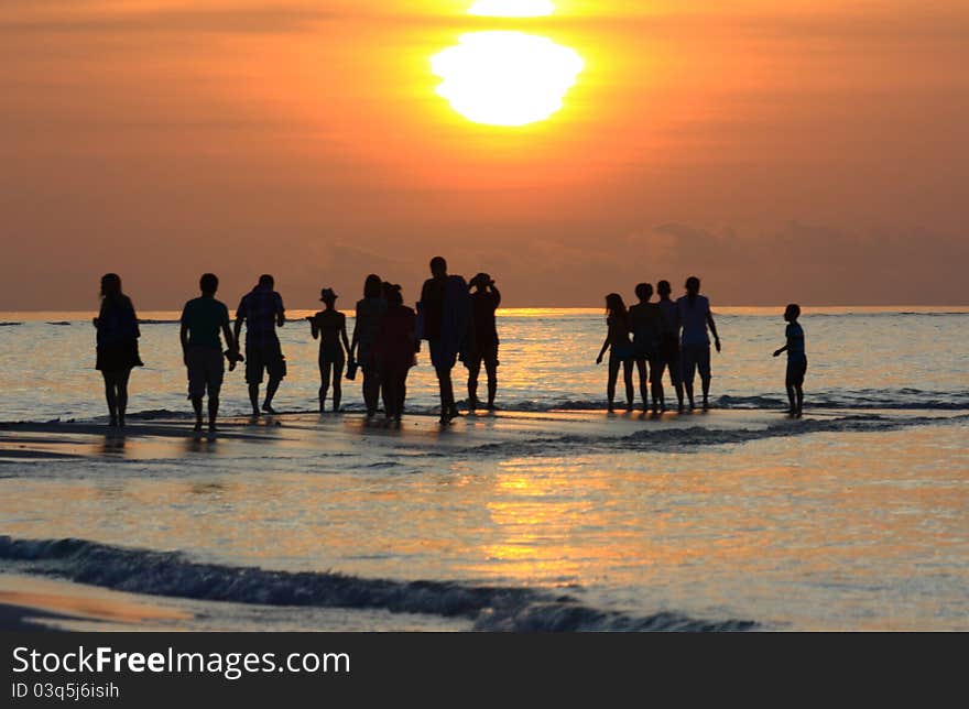 A view of a sunset in the Maldives with silouettes of people in the distance. A view of a sunset in the Maldives with silouettes of people in the distance.