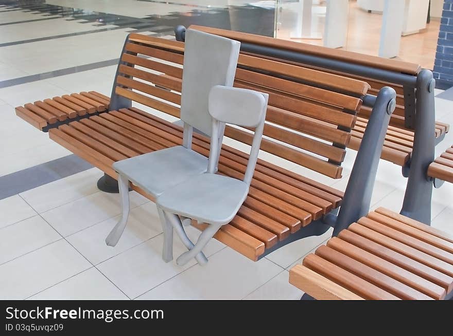 Sculpture of two chairs sitting on a bench in shopping mall. Sculpture of two chairs sitting on a bench in shopping mall