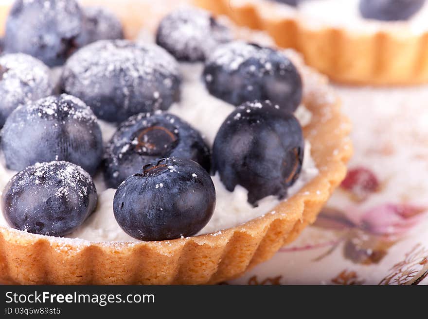 Blueberries tars on the plate with flowers. Blueberries tars on the plate with flowers