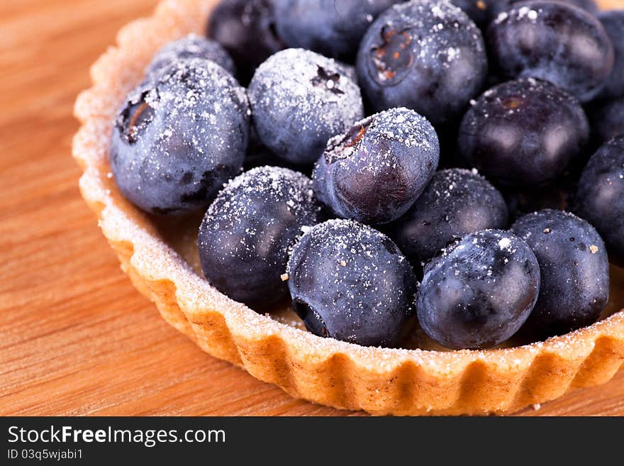 Macro picture of blueberries tart on the wooden board