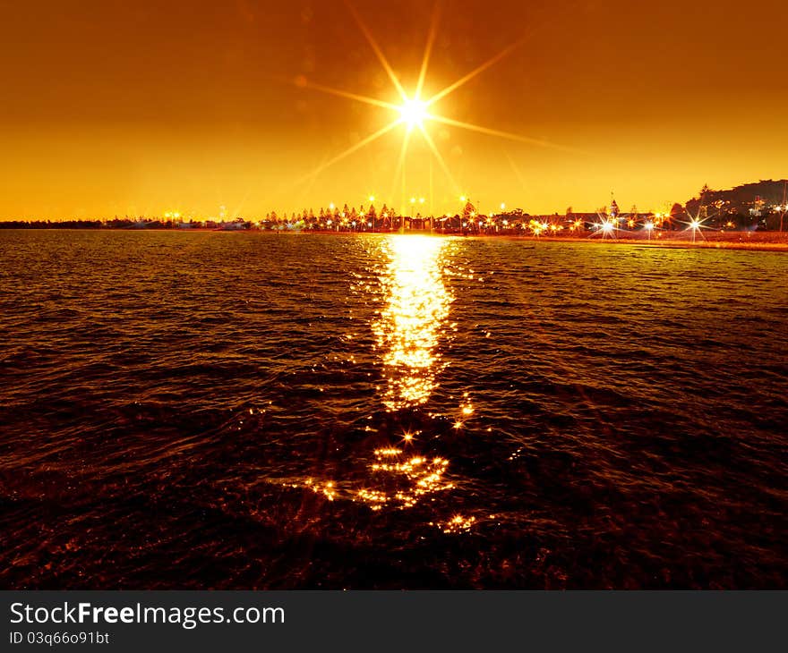 Sunset over the sea with street light background