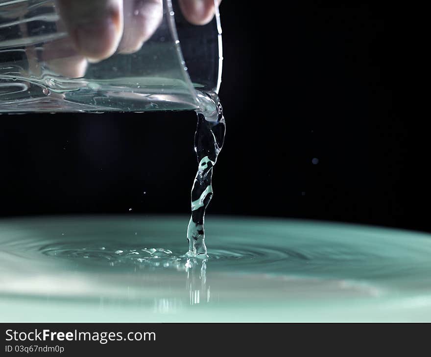 Water pouring into glass on black background