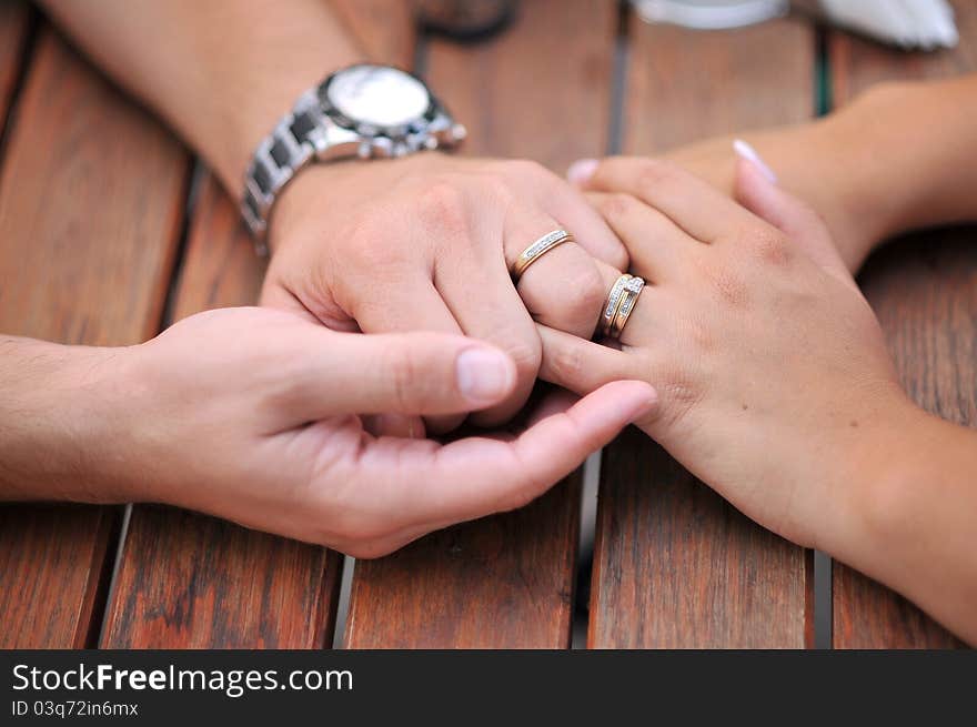 A married couple holding their hands on a table. A married couple holding their hands on a table