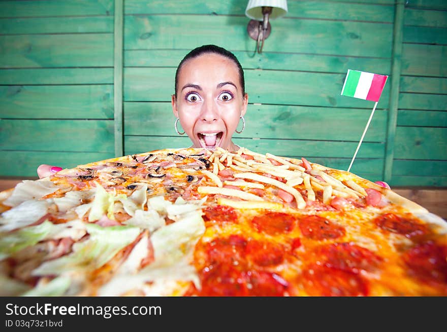 Portrait of young woman with pizza at kitchen