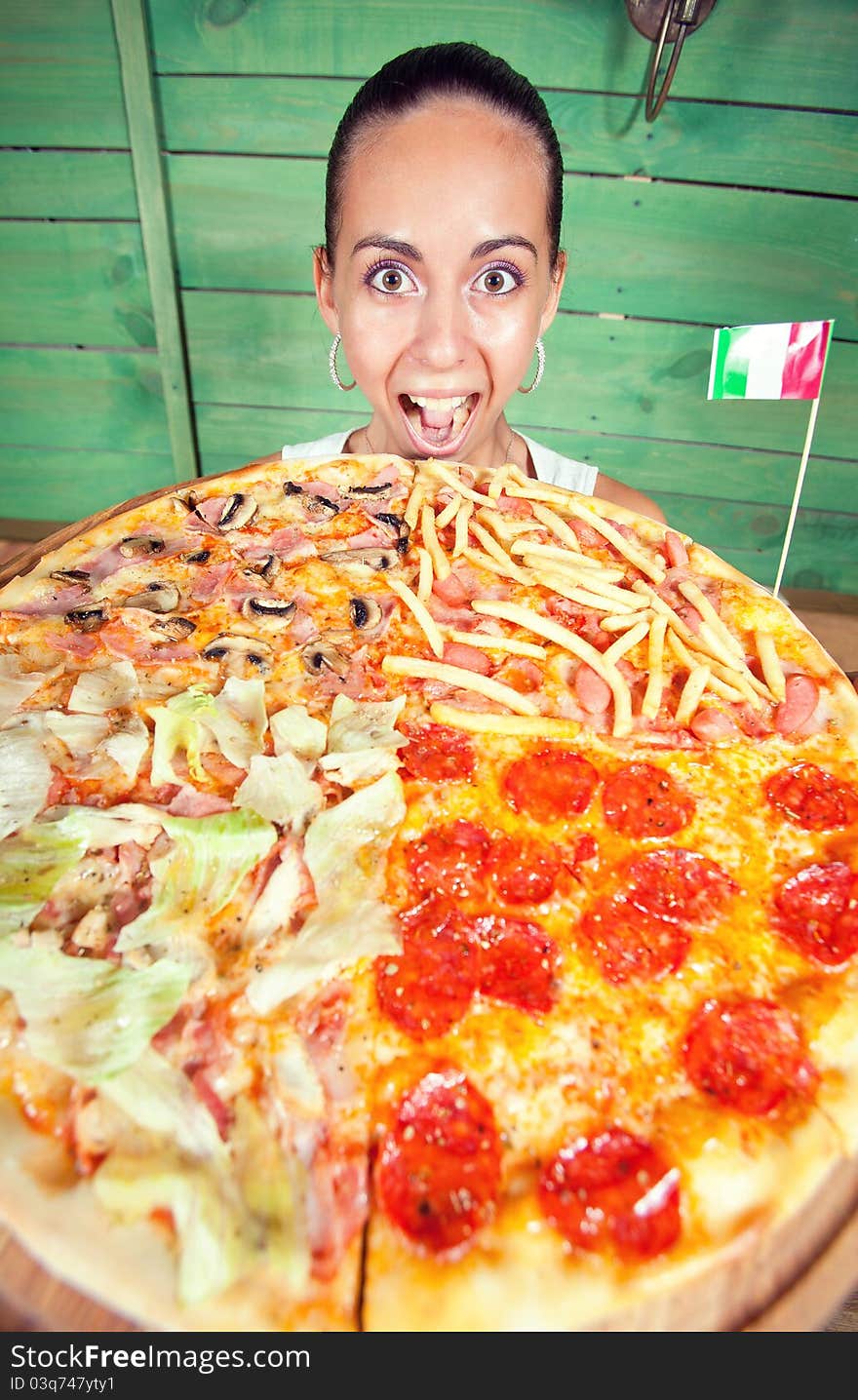 Portrait of young woman with pizza at kitchen