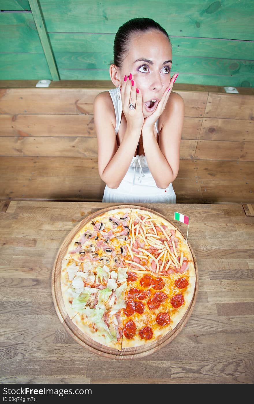 Portrait of young woman with pizza at kitchen