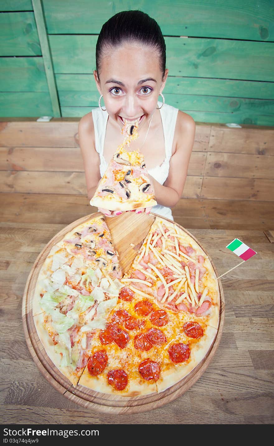 Portrait of young woman with pizza at kitchen