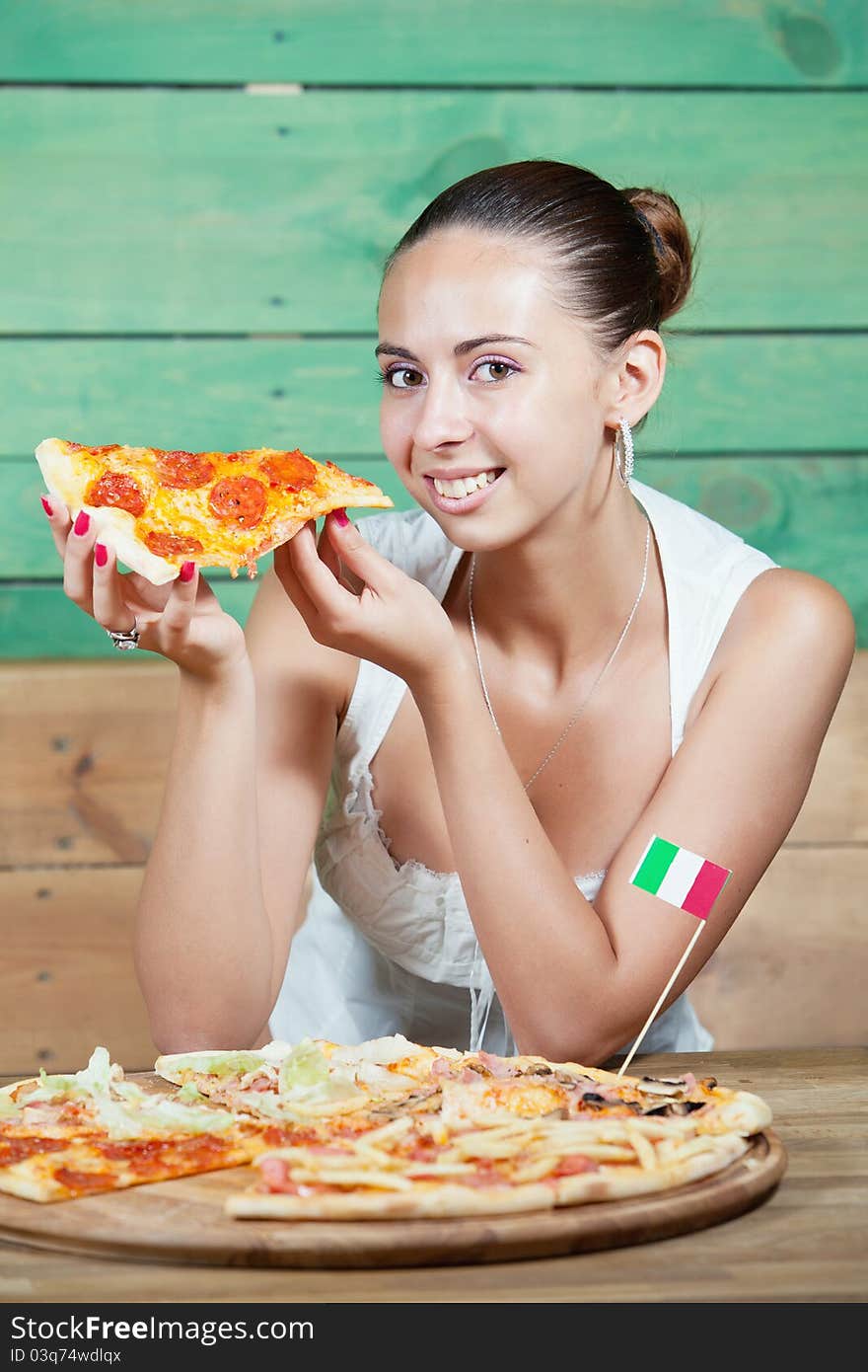 Portrait of young woman with pizza at kitchen