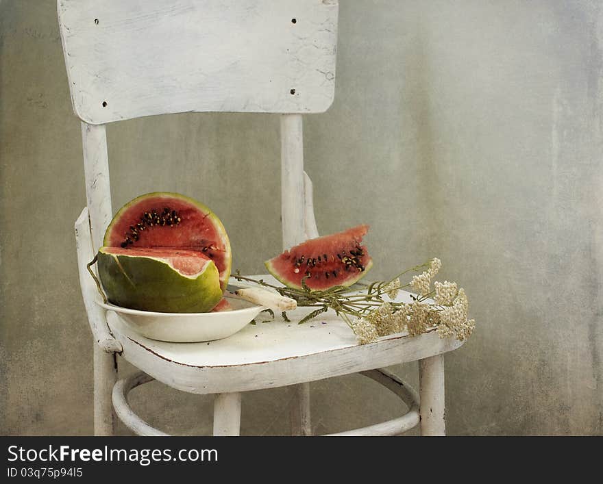 Water-melon and flowers on a white chair. Water-melon and flowers on a white chair