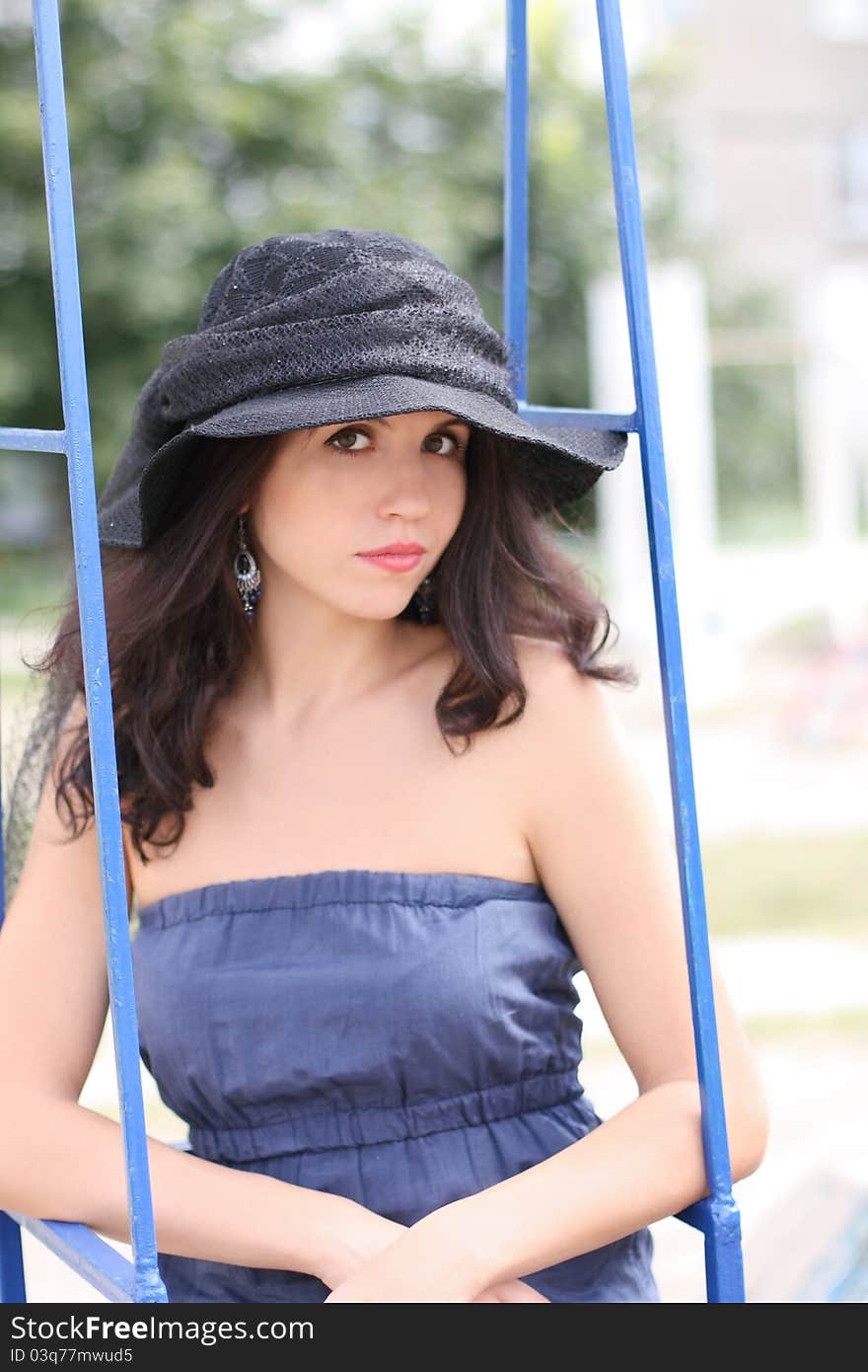 Portrait of beautiful brunette woman in black hat sitting on swing. Portrait of beautiful brunette woman in black hat sitting on swing