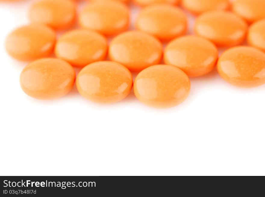 Orange tablets on a white background. Selective focus. Orange tablets on a white background. Selective focus.