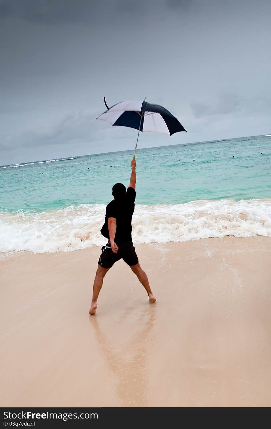 Tanned man jump with umbrella in blue sea