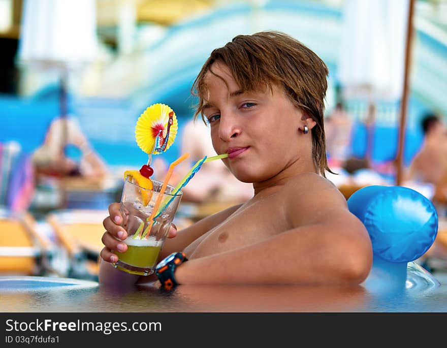 Boy with wet hair, drinking a cocktail by the swimming pool. Boy with wet hair, drinking a cocktail by the swimming pool.