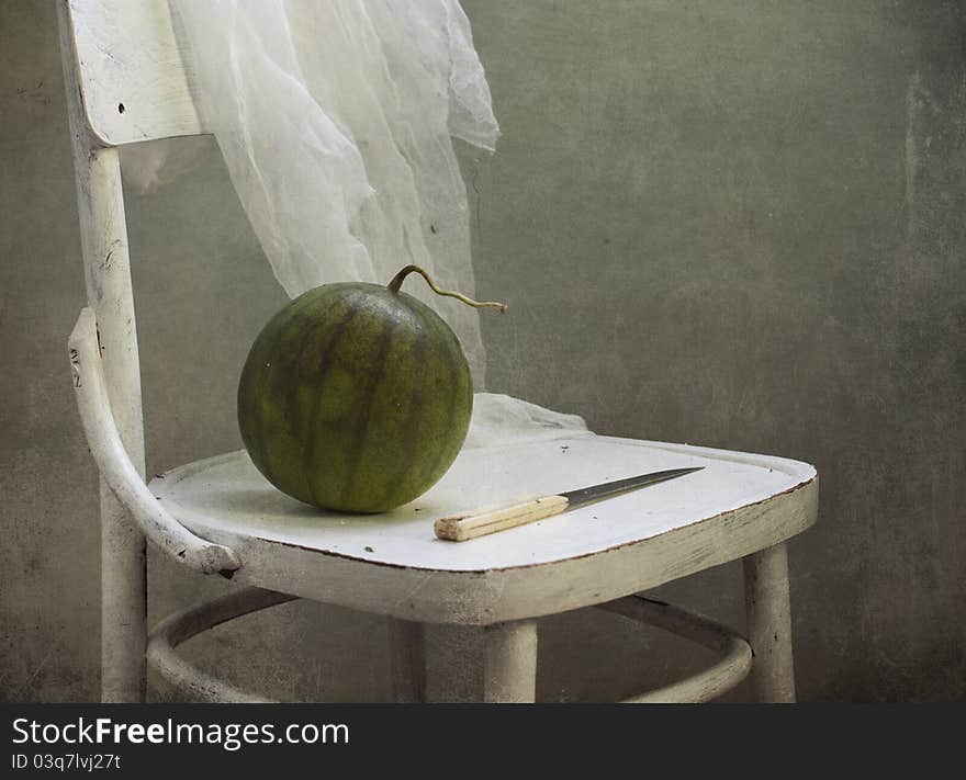 Water-melon and knife on a white chair