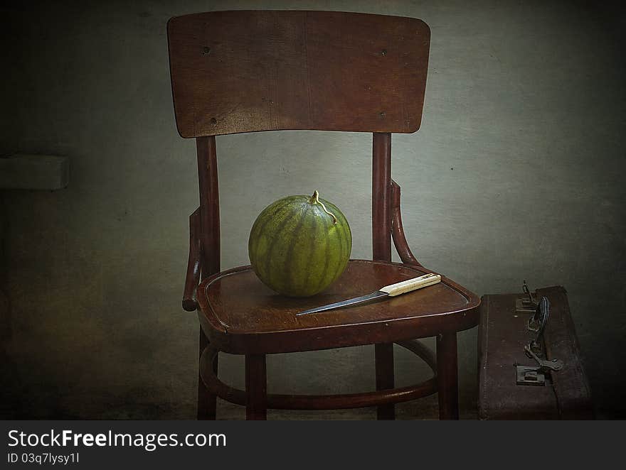 Water-melon and knife on a brown chair