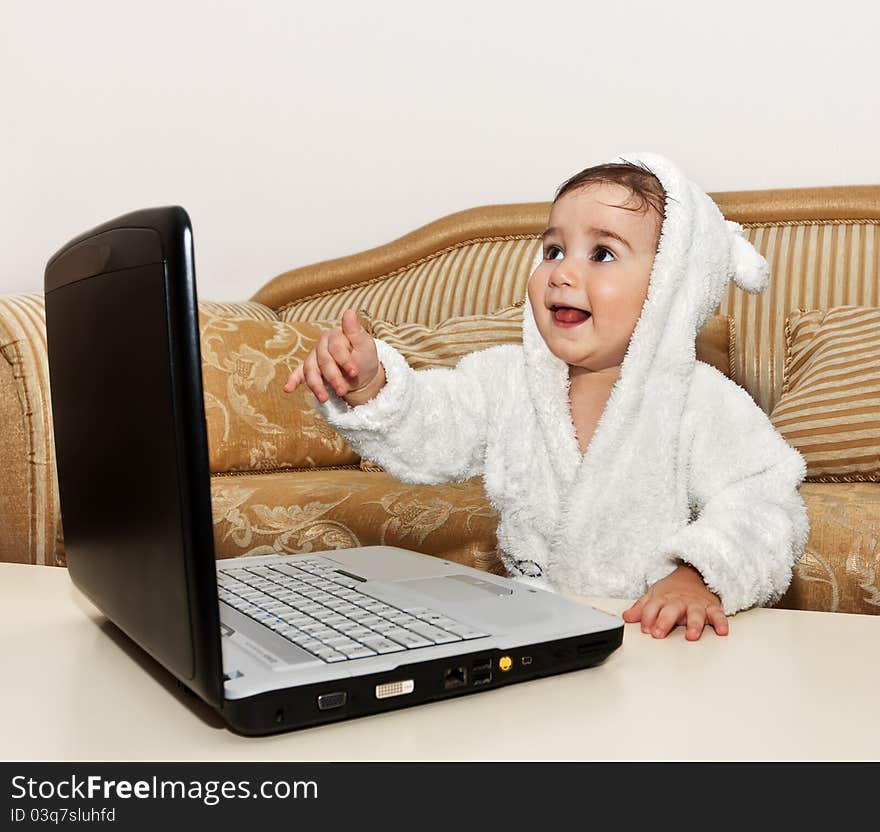 Baby boy with laptop sitting on the sofa