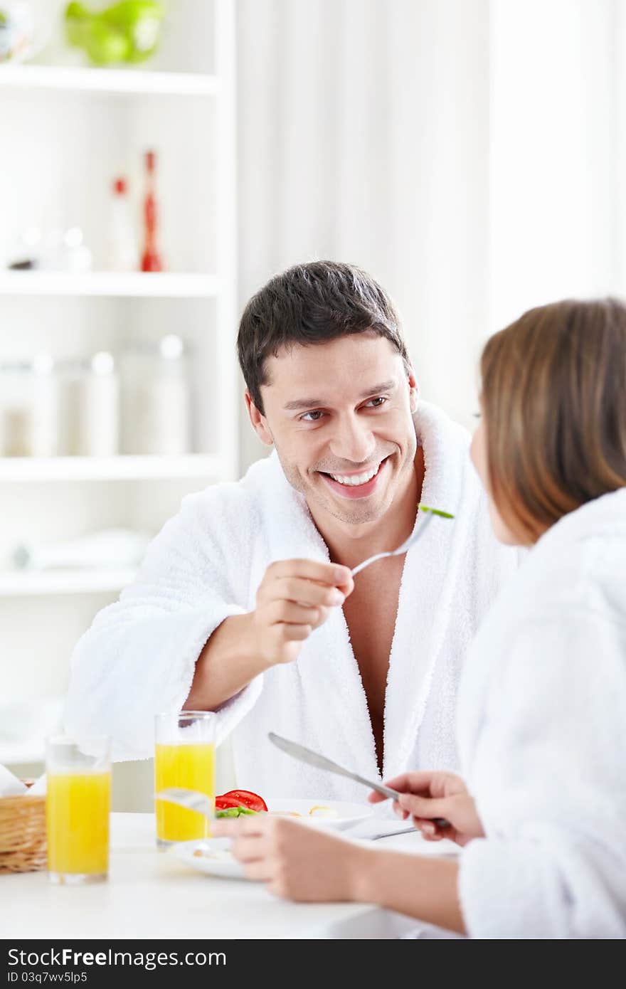 Attractive male feeds the female in the kitchen. Attractive male feeds the female in the kitchen