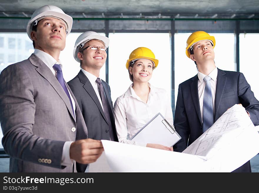 Business people in hard hats looking up at the site