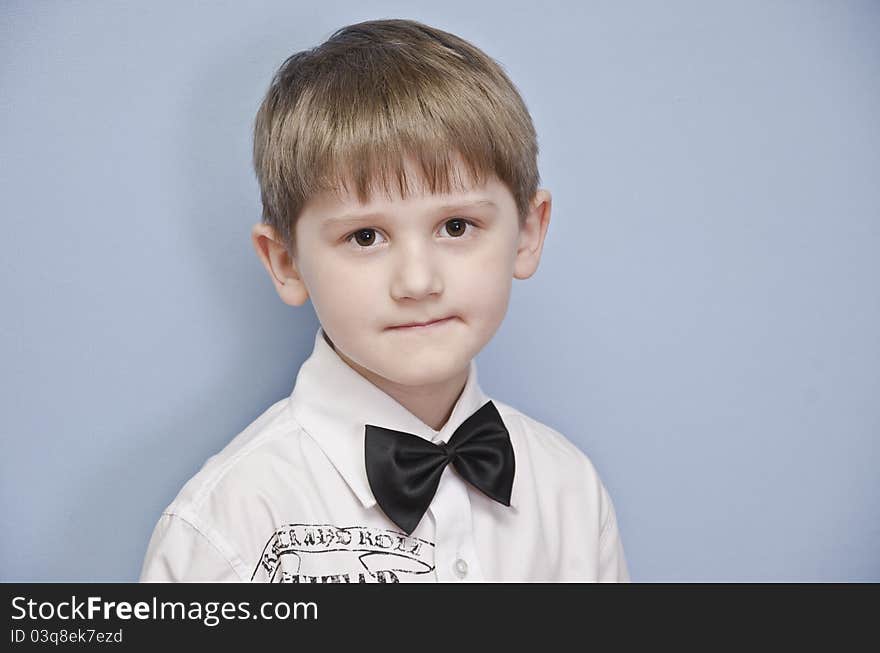 The boy in a white shirt with a tie-butterfly on a monophonic background. He is almost ready to take part in concert. The boy in a white shirt with a tie-butterfly on a monophonic background. He is almost ready to take part in concert.