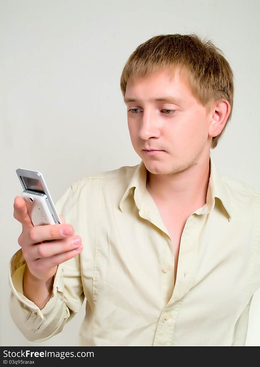 The young man in studio holds a mobile phone in hands. Dials number. The young man in studio holds a mobile phone in hands. Dials number