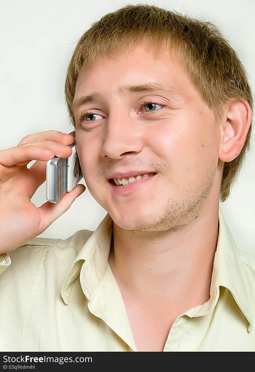 The cheerful young man speaks by phone in studio.