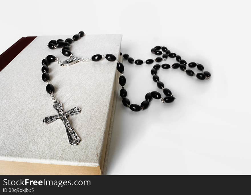 A rosary resting on the bible with white clean background. A rosary resting on the bible with white clean background