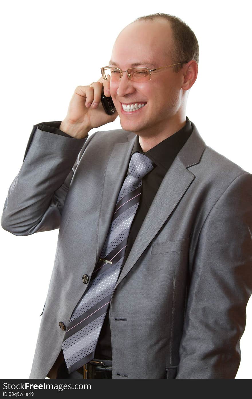 Young man in business suit, tie, glasses laughing and talking on a cell phone on a white background. Young man in business suit, tie, glasses laughing and talking on a cell phone on a white background