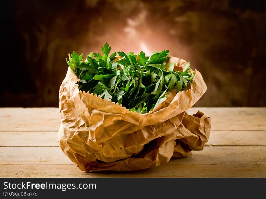 Photo of fresh parsley inside a paper bag on wooden table