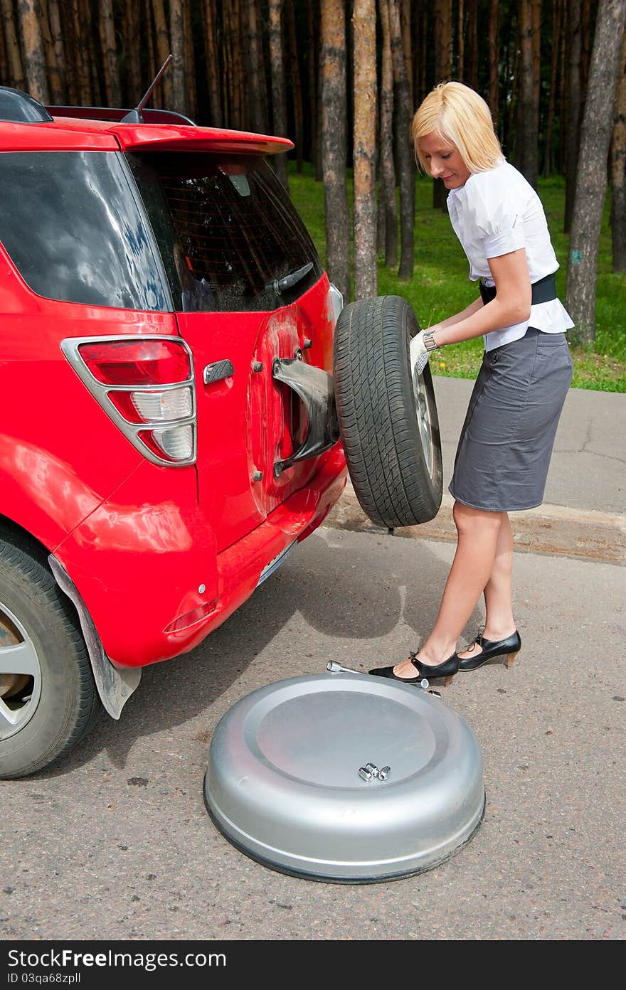 Blonde changing tire alone on a road. Blonde changing tire alone on a road